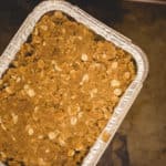 frozen apple crisp in container sitting on top of baking sheet