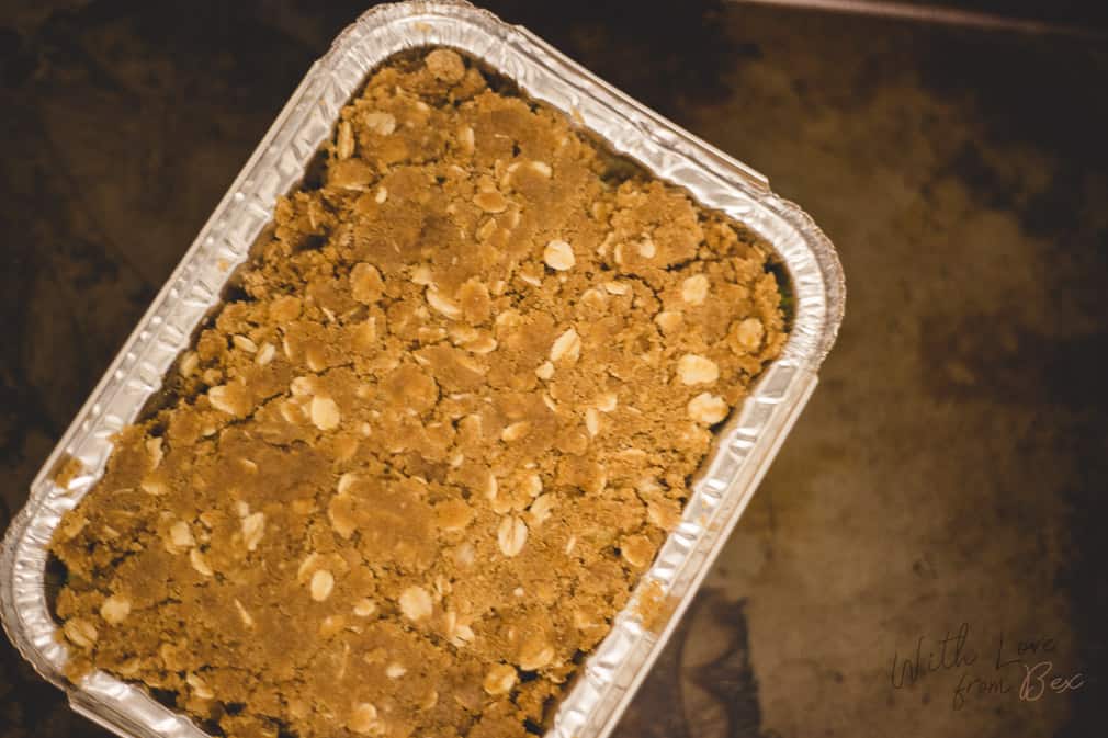 frozen apple crisp in container sitting on top of baking sheet