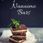 three maple bacon nanaimo bars stacked on top of each other topped with a mint leave against a black and gray background