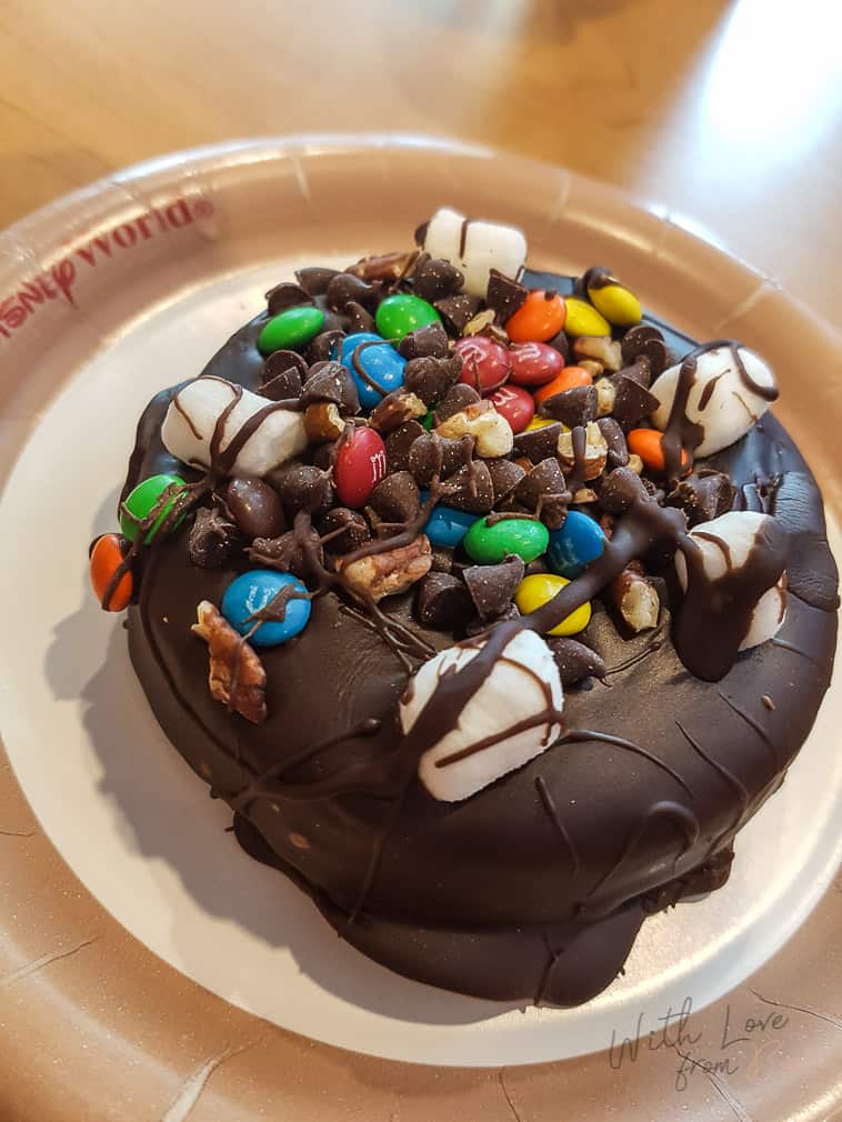 round brownie, covered in dipped chocolate and topped with mms, marshmellows, and chocolate