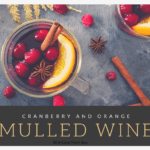 Two clear glasses of mulled red wine with cranberries and a slice of orange